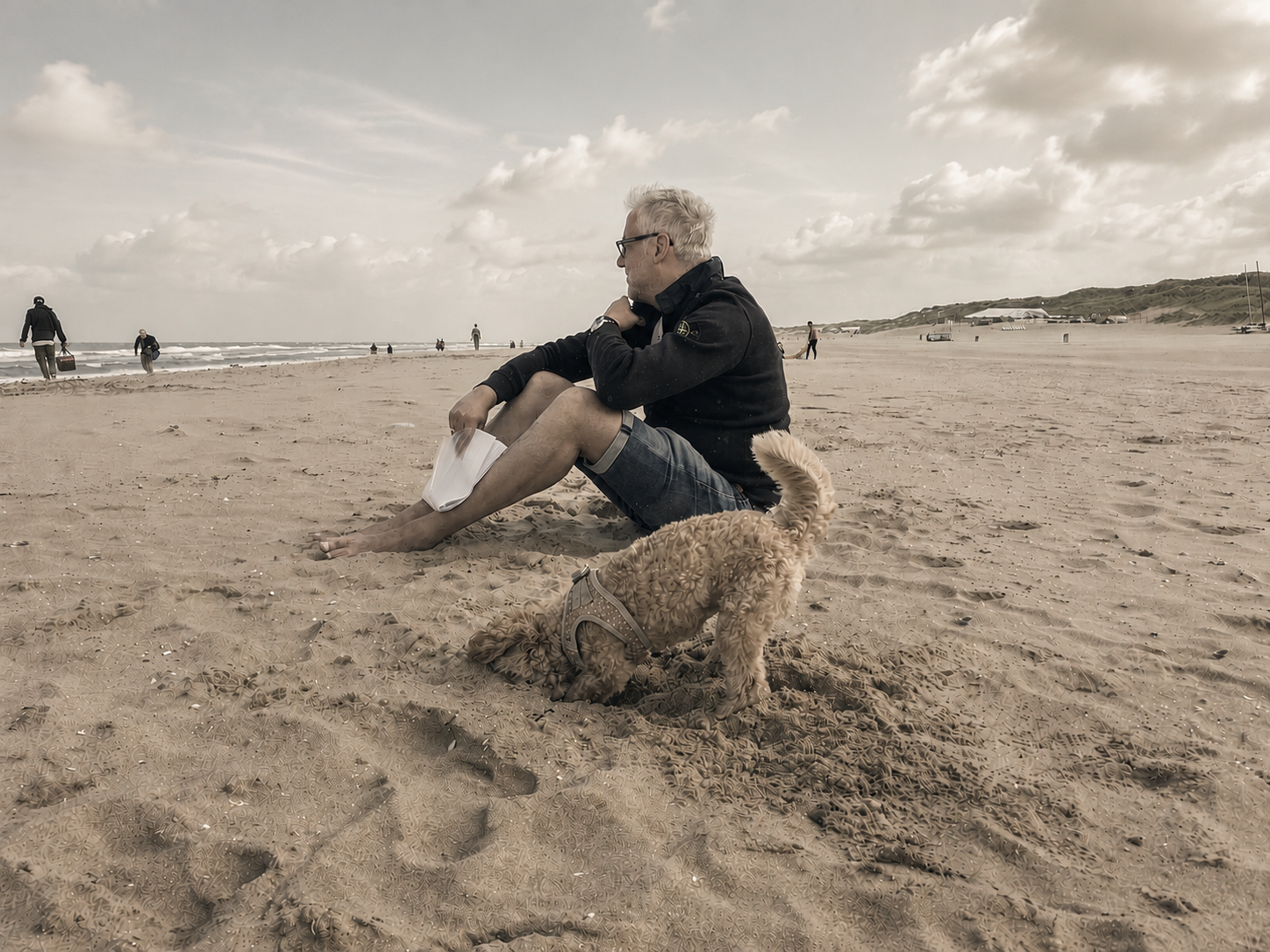 Reinhard Köhler sitzt mit seinem Hund am Strand und blickt aufs Meer